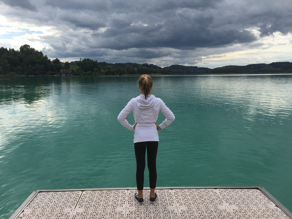 Girl standing on pier looking out over lake