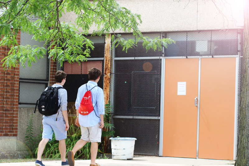 Two boys with backpacks walking into a school