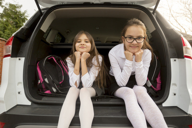 Image of 2 girls sitting in open trunk of suv
