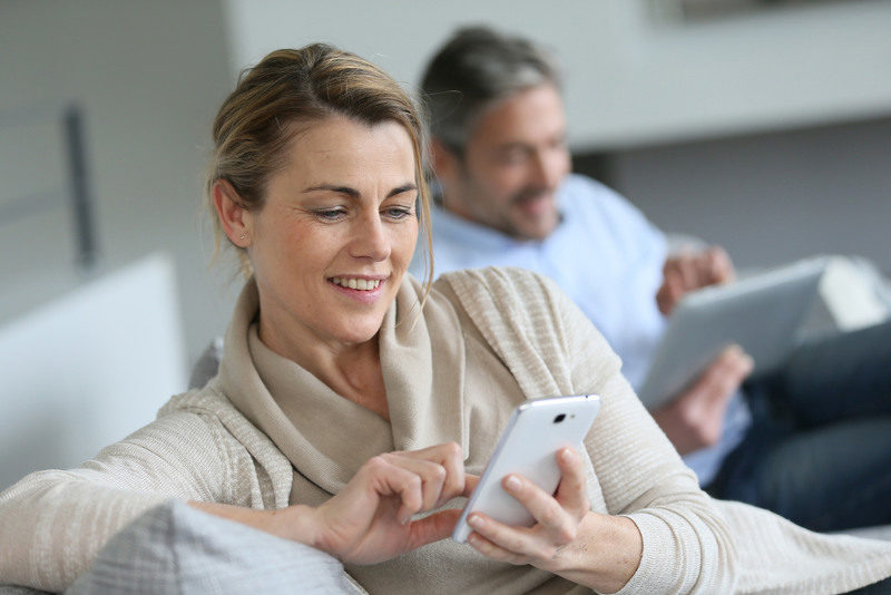 woman sitting on a sofa looking at her smart phone