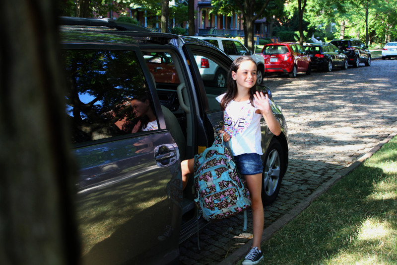 child getting into car with backpack